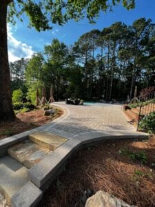 Brick-paved garden pathway with steps leading to a seating area surrounded by trees.