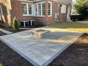 Newly constructed brick fire pit on a paved patio with a residential backdrop.